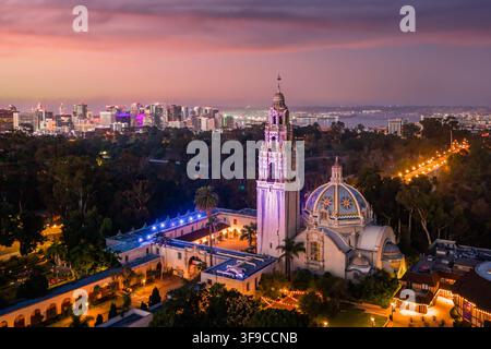 Vista aerea del Balboa Park con la California Tower illuminata e il Museum of Us all'alba, con lo skyline di San Diego sullo sfondo, San Diego Foto Stock