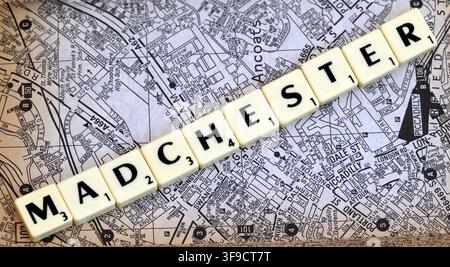 Piastrelle con lettere Madchester su una mappa stampata della città di Manchester, che evocano la scena musicale Mad Frit e l'identità culturale della città. Foto Stock