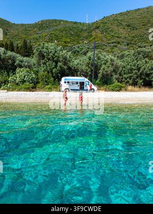 Il sole dipinge il paesaggio sereno della spiaggia di Kamari, Lefkada, dove i visitatori godono delle acque turchesi mozzafiato. Foto Stock