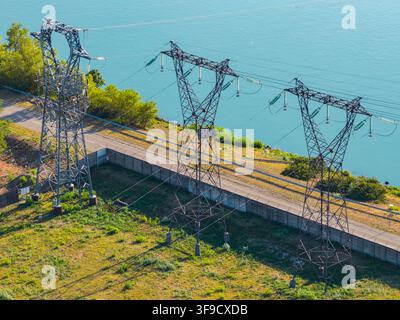 Veduta aerea di tralicci di trasmissione ad alta tensione e linee elettriche vicino a un fiume a Saulce-sur-Rhone, Alvernia-Rodano-Alpi, Francia. Foto Stock