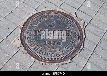 YELETS, RUSSI - 03 LUGLIO 2026: Una botola d'acqua a forma di una vecchia moneta da cinque rubli del 1874 in una giornata di sole. Yelets, regione di Lipetsk Foto Stock