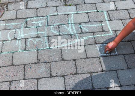 Prima vista di un bambino che disegna la campana con la gessica sul marciapiede lastricato. Svezia. Foto Stock