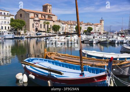 Una barca tradizionale blu in legno ormeggiata nel porto di La Ciotat con la chiesa storica e le case colorate della città in Provenza, Francia. Foto Stock
