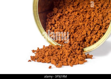 Il caffè istantaneo viene versato da una lattina di metallo. Caffè in polvere su sfondo bianco. Foto Stock