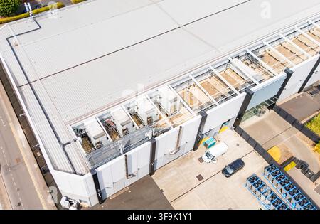 Immagine aerea con drone del tetto di un moderno centro dati, con unità di climatizzazione industriali esistenti e una struttura vuota prefabbricata per l'espansione Foto Stock