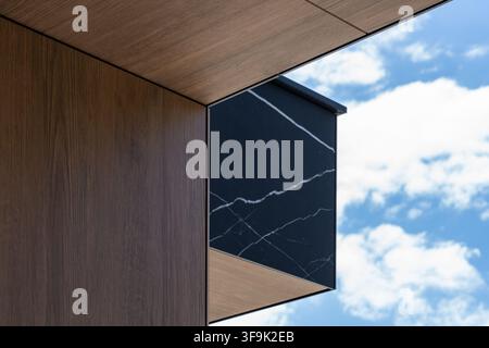 Dettaglio del cornicione di architettura moderna che combina marmo venato e piastrella in legno scuro, contrasto di materiali della facciata della casa di lusso Foto Stock