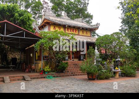 Tempio Doi Co Cau Ma, Vietnam - 12 ottobre 2023: Edificio di pagoda con tetto intricato e vegetazione circostante Foto Stock