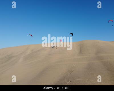 Vista aerea di parapendisti che planano sopra le vaste dune di sabbia di Huacachina a Ica, Ica, Perù. Foto Stock