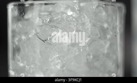 Ghiaccio tritato che riempie un bicchiere per bevande fredde rinfrescanti, dettaglio macro che mostra frammenti ghiacciati trasparenti Foto Stock