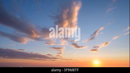 Un cielo drammatico al tramonto mette in mostra colori vivaci e nuvole soffici, creando un'atmosfera serena mentre la giornata volge al termine. Foto Stock