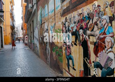 Affresco di musicisti con una donna che cammina lungo il vicolo. Carrer del Pintor Fillol, Barrio el Carmen, Valencia. Spagna. Foto Stock