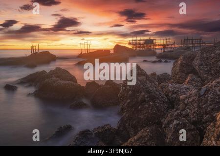 Vista del Trabocco Spezzacatena al tramonto con costa rocciosa e mare calmo a Rocca San Giovanni, Provincia di Chieti, Italia. Foto Stock