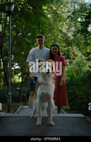 Cane a fuoco mentre una giovane coppia sorride sullo sfondo. Stile di vita all'aperto e amore nella natura. Foto Stock