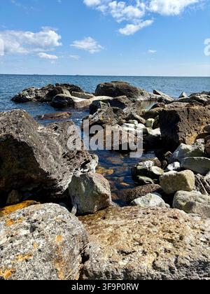 Grandi rocce costiere contro il profondo mare blu e il cielo nuvoloso Foto Stock