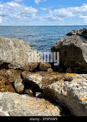 Grandi rocce costiere contro il profondo mare blu e il cielo nuvoloso Foto Stock