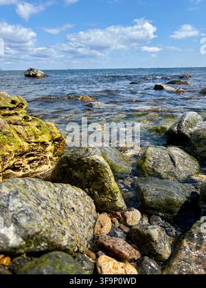 Grandi rocce costiere contro il profondo mare blu e il cielo nuvoloso Foto Stock