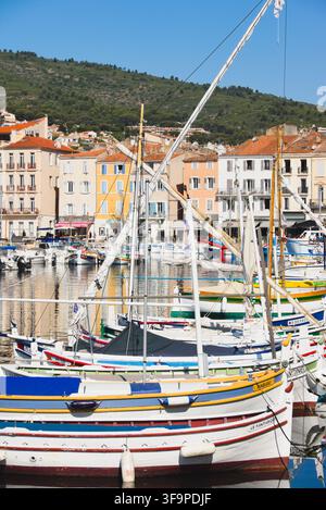 Vista verticale delle colorate barche da pesca tradizionali Pointu ormeggiate nel vecchio porto di La Ciotat, Francia, con le facciate della città sullo sfondo. Foto Stock