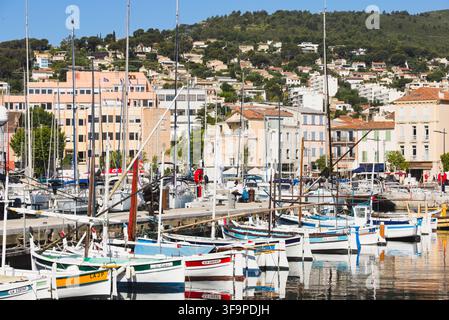 Filiera di tradizionali barche Pointu ormeggiate nel vecchio porto di La Ciotat, Francia, con edifici colorati e colline sullo sfondo. Foto Stock