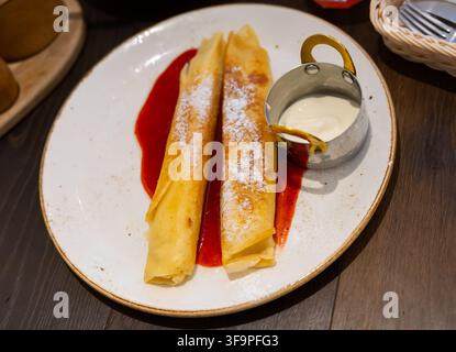 Il dessert nel ristorante è costituito da due pancake arrotolati, ripieni di cagliata Foto Stock