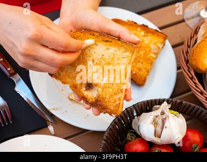 Mano di donna che strofina crostini all'aglio Foto Stock