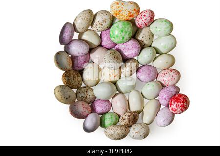 Una fotografia in studio che mostra un mucchio disordinato di uova ricoperte di cioccolato colorate e maculate simili a uova di птице in miniatura, disposte su uno sfondo bianco pulito Foto Stock