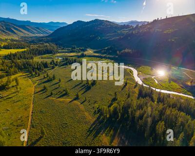 Panoramica aerea scenografica al tramonto che cattura Granite Creek che si snoda attraverso la valle delle montagne Teton Foto Stock