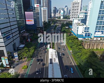 Vista aerea della trafficata autostrada Sudirman con traffico intenso, grattacieli moderni e un ponte pedonale a Jakarta, Jakarta, Indonesia. Foto Stock