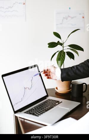 Uomo che analizza la tendenza del prezzo dei dati Bitcoin. Broker di investimenti che negozia criptovalute Bitcoin utilizzando telefono e laptop Foto Stock