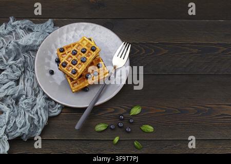 Goffrette belgiche con miele e frutti di bosco freschi, mirtillo su sfondo rustico scuro. Foto Stock