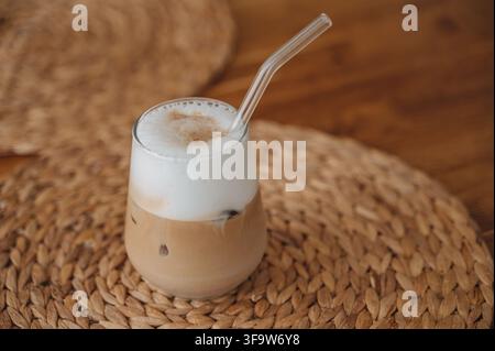 Bevanda al caffè a strati o latte macchiato con una cannuccia su un tovagliolo intrecciato, bevanda rinfrescante estiva. Foto di alta qualità Foto Stock