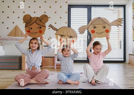 Bambini che esplorano emozioni ed espressioni facciali attraverso il gioco creativo. Foto Stock