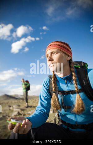Una donna che utilizza una bussola durante l'escursionismo con lo zaino. Foto Stock
