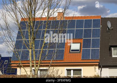 Pannelli solari che coprono un tetto piastrellato, producendo energia elettrica sostenibile per una casa residenziale Foto Stock