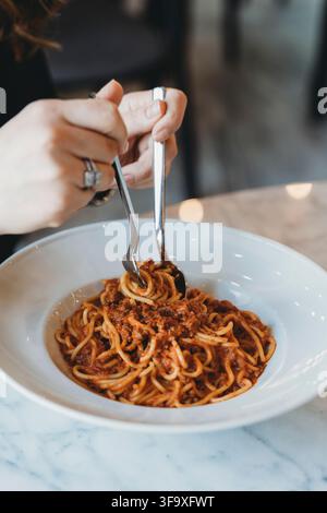 Donna che fa roteare deliziose spaghetti in una ciotola bianca Foto Stock