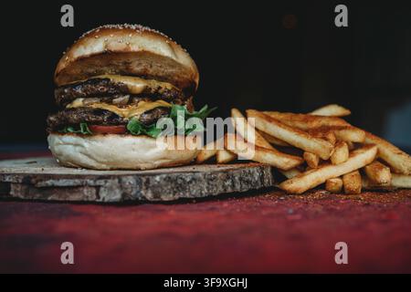 Double cheeseburger gourmet con patatine fritte condite Foto Stock