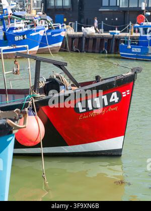 ### Caption Barche da pesca ormeggiate nel porto di Whitstable, Kent, Inghilterra, con tradizionali edifici portuali in legno nero e attrezzature da pesca. Foto Stock
