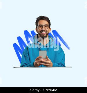 Giovane uomo sorridente che tiene uno smartphone in una felpa blu con cappuccio, concetto di tecnologia Foto Stock
