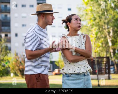 Coppia che vive un conflitto relazionale discutendo le loro differenze in uno spazio verde urbano. Foto Stock