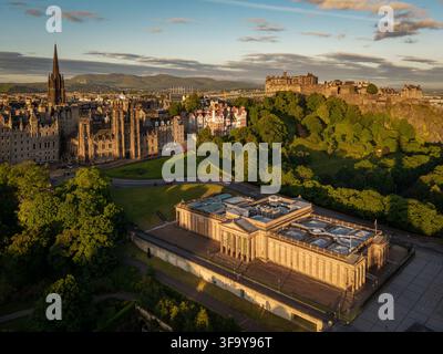 Vista aerea della National Gallery of Scotland e del Castello di Edimburgo circondati da architettura storica e vegetazione rigogliosa durante l'ora dorata a Edinb Foto Stock