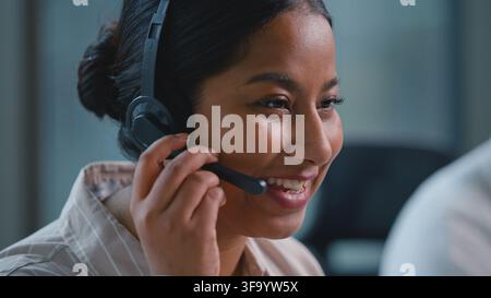 Primo piano di una receptionist araba sorridente e felice che parla in un microfono per cuffie, donna d'affari indiana etnica gioiosa spensierata donna d'affari parla in Foto Stock