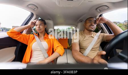 Stanca giovane coppia afroamericana seduta in macchina con espressioni tese Foto Stock