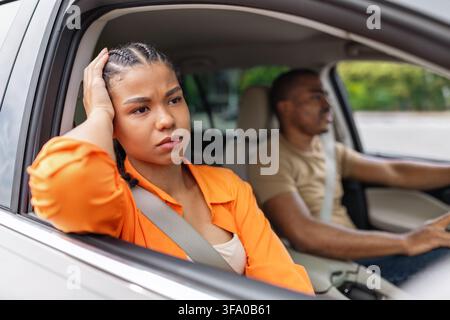 Giovane donna nera preoccupata seduta in macchina che si tiene la testa, con aria turbata Foto Stock
