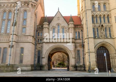 Architettura gotica storica alla Manchester University di Manchester, Regno Unito, caratterizzata da un grande arco in pietra, finestre ornate e imponenti edifici accademici Foto Stock