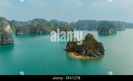 Vista aerea di isolotti di calcare che si innalzano dall'acqua smeraldina nella baia di Ha Long, Quang Ninh, Vietnam, che mostrano formazioni carsiche drammatiche e vegetazione tropicale Foto Stock