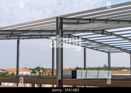 La struttura scheletrica di un grande edificio viene eretta con pesanti travi e colonne in acciaio sullo sfondo di nuvole sparse Foto Stock