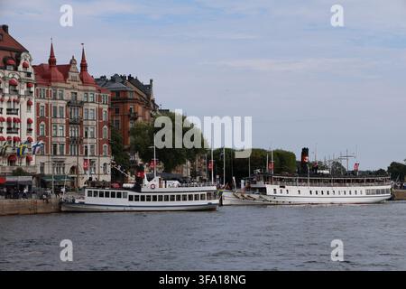 Barche turistiche ormeggiate ad un molo nel centro di Stoccolma in una giornata estiva di agosto. Foto Stock