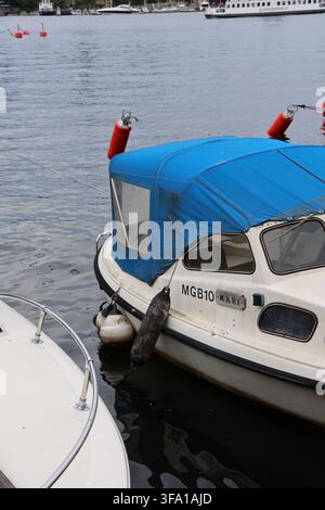 Piccole barche ormeggiate lungo il molo di Skeppsholmen a Stoccolma, Svezia, con il lungomare e le acque calme nelle vicinanze. Foto Stock