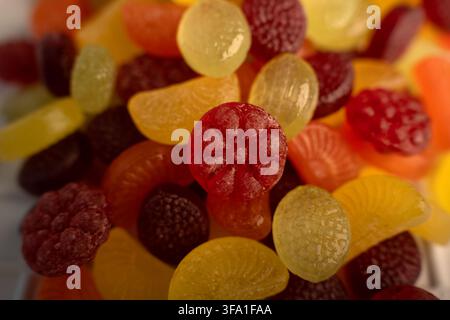 Macro close-up di vari dolci duri colorati a forma di frutta e gumdrops ammucchiati in una ciotola poco profonda, superfici traslucide lucide con zucchero strutturato Foto Stock