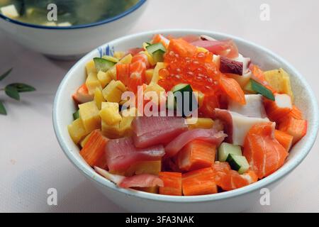 Una ciotola di pesci freschi tagliati a cubetti tra cui tonno, uova di salmone, bastoncini di granchio, ecc. che coprono il fiume giapponese chiamato chirashi don servito con miso s Foto Stock