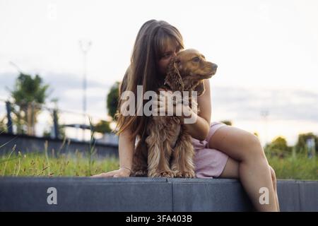 Momento tenero di una donna che abbraccia il suo cane durante una serata in città Foto Stock